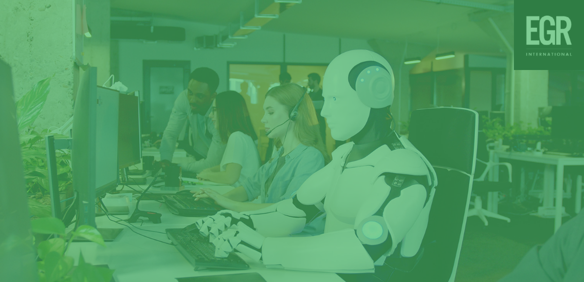 EGR Blog: Friction and the Role of AI in the Customer Experience - image of a robot sitting at a computer terminal, wearing a headset with a group of human customer service agents